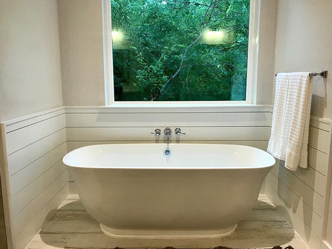 free standing bathtub in front of a window